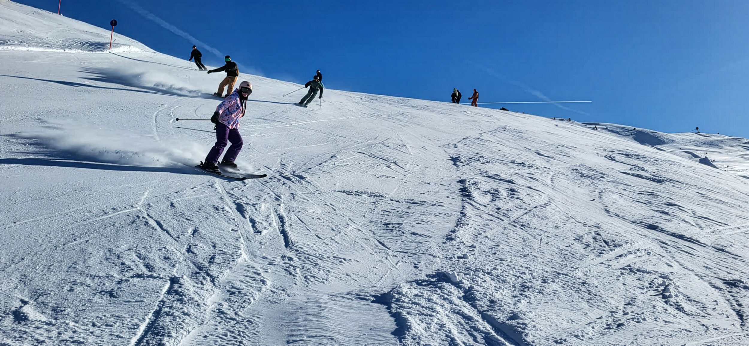 Skifahrer am Hang vor blauem Himmel